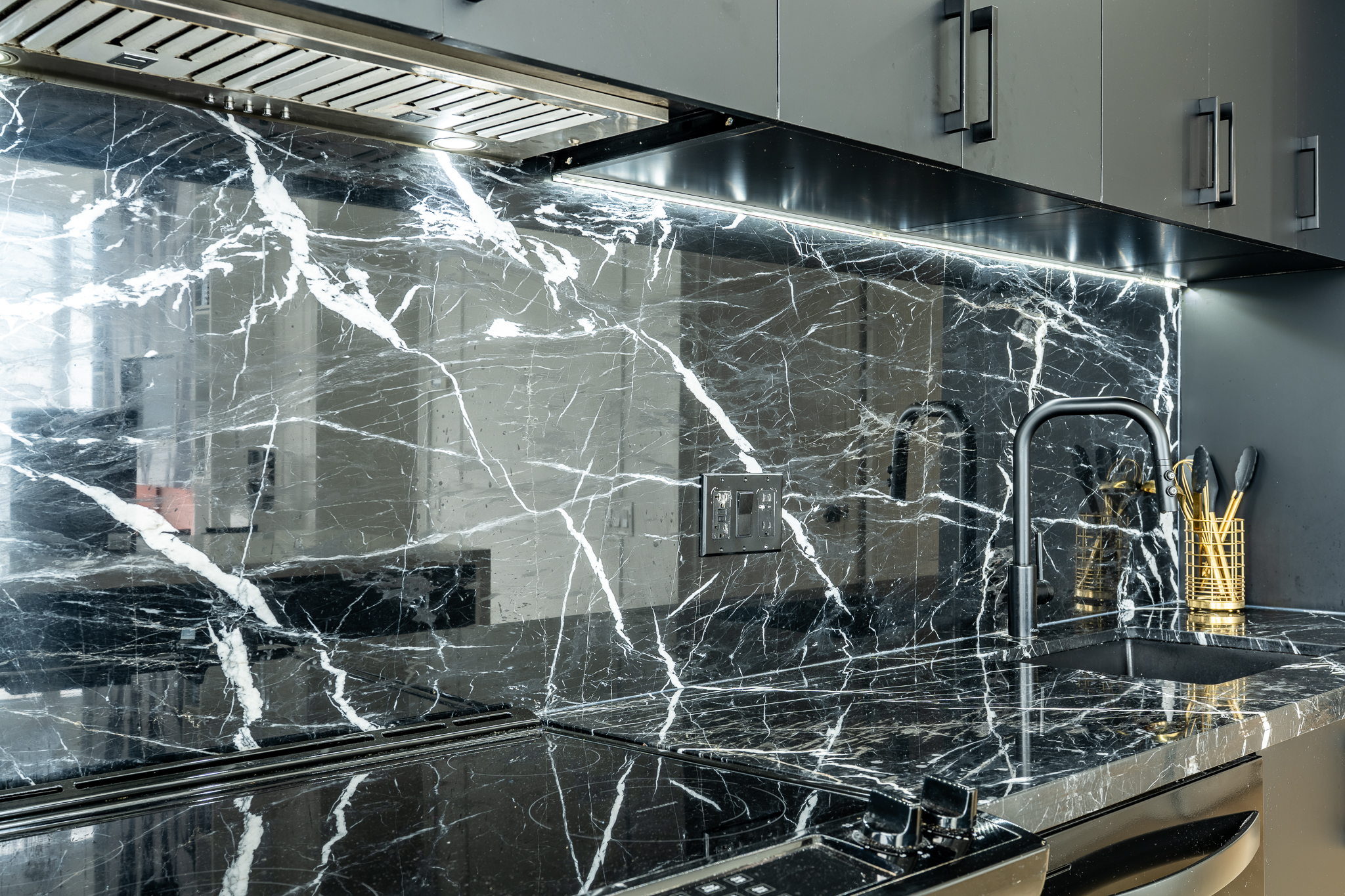 Close-up of full slab marble kitchen backsplash with brushed gold fixtures